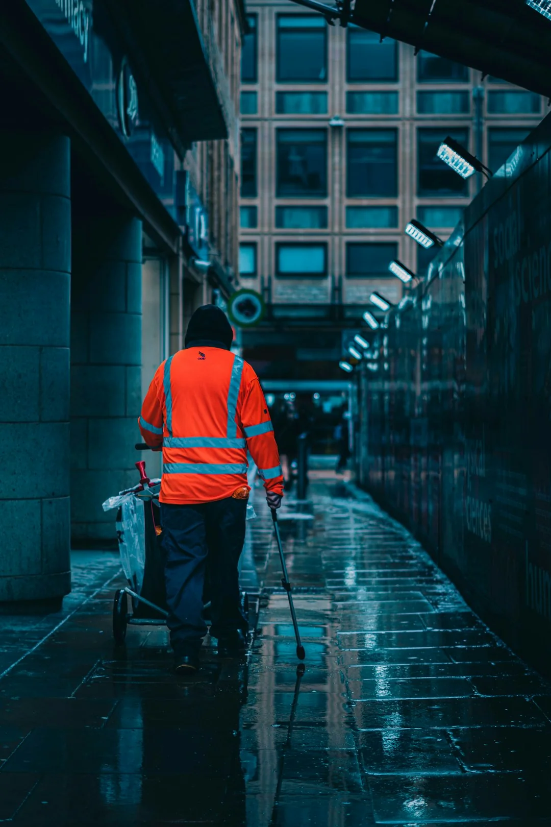 Un homme nettoie les vitres d'un gratte-ciel à l'aide d'un harnais, illustrant le travail en hauteur en milieu urbain.